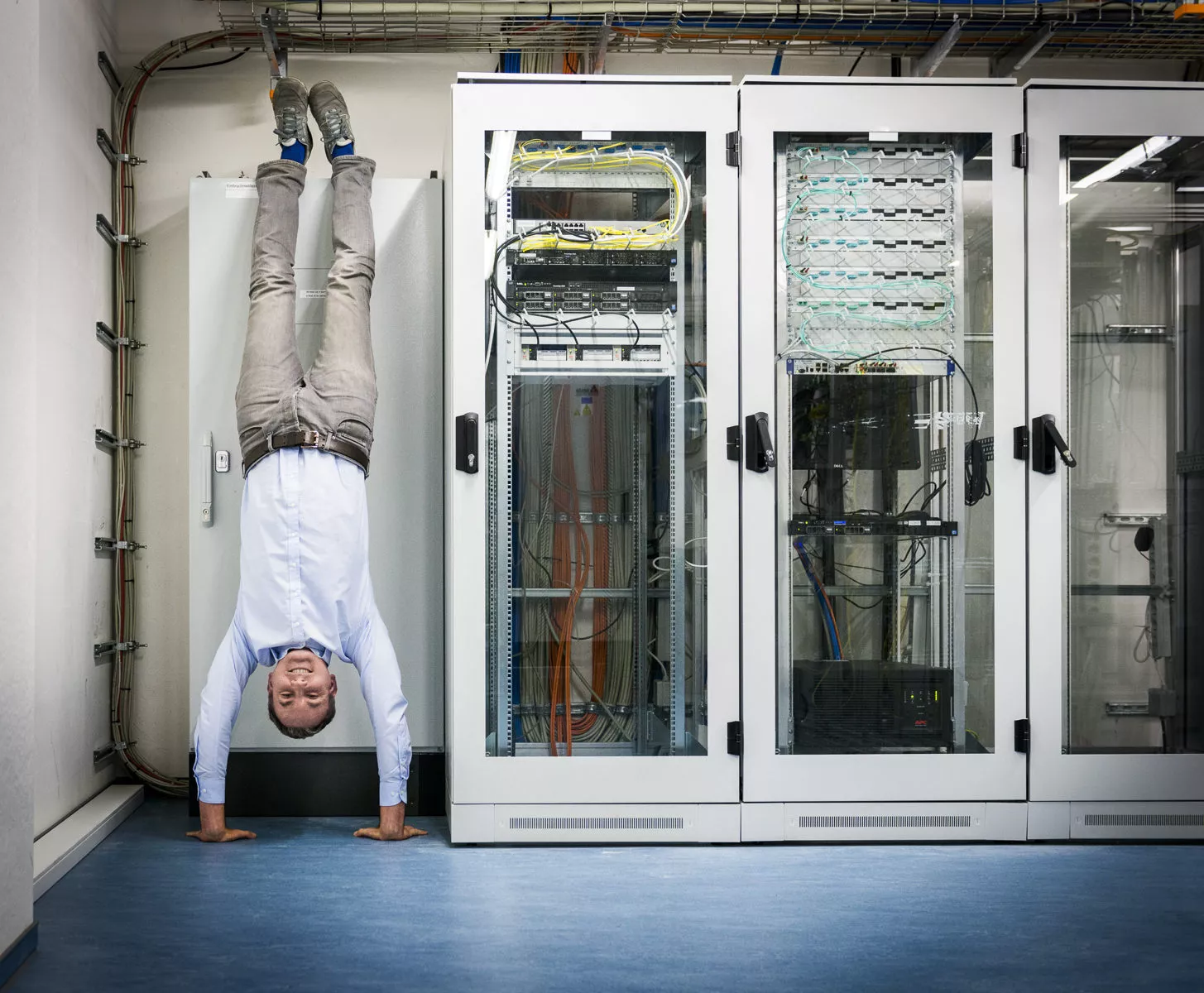 IT-Mitarbeiter macht Handstand inmitten eines Serverraumes
