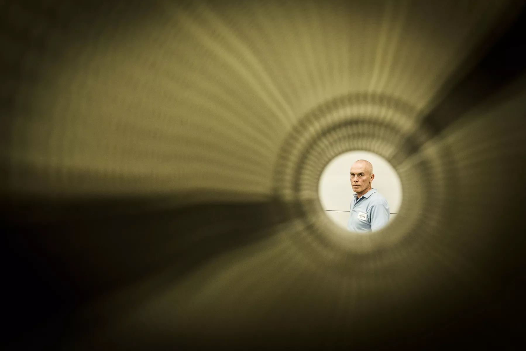 Blick durch ein Luftrohr auf einen Mitarbeiter, der in die Kamera schaut